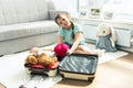 Cute little girl traveler packing a suitcase for a trip. Girl sitting at home on the floor near the sofa next to toys Royalty Free Stock Photo