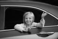 Cute little girl traveling in the car and observing nature from open window. Little girl waving hand for good bye in the Royalty Free Stock Photo