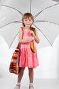 Cute little girl with umbrella and bag on her shoulder posing on a white background Royalty Free Stock Photo