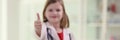 Cute little girl in uniform of medic shows thumb up gesture