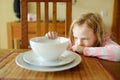 Cute little girl unwilling to eat her soup. Child having a dinner at home