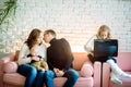 Cute little girl is using a digital tablet while lying on the floor at home, in the background her handsome father and mother with Royalty Free Stock Photo