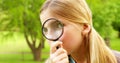 Cute little girl using magnifying glass in park