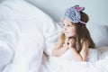 Cute little girl wake up in bed in the morning wearing grey bunny sleep mask. Happy adorable kid under soft white blanket. Sweet Royalty Free Stock Photo