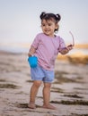 Cute little girl walking on sandy beach, holding bucket and sunglasses. Warm day. Happy childhood. Summer vacation. Holiday Royalty Free Stock Photo