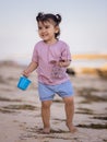 Cute little girl walking on sandy beach, holding bucket and sunglasses. Warm day. Happy childhood. Summer vacation. Holiday Royalty Free Stock Photo