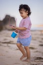 Cute little girl walking on sandy beach, holding bucket and sunglasses. Warm day. Happy childhood. Summer vacation. Holiday Royalty Free Stock Photo