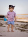 Cute little girl walking on sandy beach and holding bucket. Warm sunny day. Happy childhood. Summer vacation. Holiday concept. Royalty Free Stock Photo