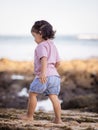 Cute little girl walking on sandy beach. Warm sunny day. Happy childhood. Summer vacation. Holiday at the sea. Baby girl wearing Royalty Free Stock Photo