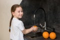 cute little girl washes oranges at home in the kitchen and smiles Royalty Free Stock Photo
