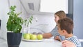 A cute little girl is washing fruits in a modern kitchen with her brother. Children at home.