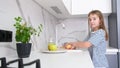 A cute little girl is washing fruits in a modern kitchen with her brother. Children at home.