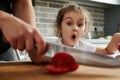 Beautiful little girl watches her mother cutting tomato on a cutting board. Mother and daughter preparing food together Royalty Free Stock Photo