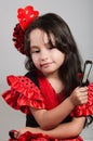 Cute little girl wearing beautiful red and black dress with matching head band, posing for camera using chinese hand fan Royalty Free Stock Photo