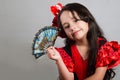 Cute little girl wearing beautiful red and black dress with matching head band, posing for camera using chinese hand fan