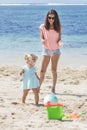 Cute little girl wearing blue dress playing beach ball with her Royalty Free Stock Photo