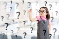 Cute little girl wearing business dress and writing question mark. Office background. Royalty Free Stock Photo