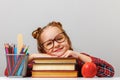 Cute little girl wearing glasses is sitting at the table, leaning on thick books. Education concept Royalty Free Stock Photo