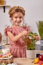 Little girl is making a homemade cake with an easy recipe at kitchen against a white wall with shelves on it. Royalty Free Stock Photo
