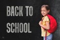 Little girl wearing red backpack   standing against blackboard , back to school concept Royalty Free Stock Photo