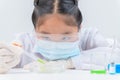 Cute little girl wearing safty glasses making experiment and using dropper in chemical laboratory