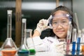 Cute little girl wearing safty goggle and lab coat making experiment