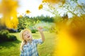 Cute little girl wearing straw hat admiring tall yellow coneflowers on sunny summer day. Child and flowers, summer, nature and fun