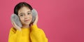 Cute little girl wearing stylish earmuffs on pink background