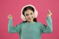 Cute little girl wearing stylish earmuffs on pink