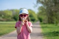 A cute little girl wearing sunglasses enjoys ice cream in park Royalty Free Stock Photo