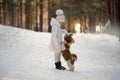 Cute little girl in a white coat with a dog walk in the winter forest. A child is training a dog. Obedience training. Children and