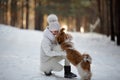 Cute little girl in a white coat with a dog walk in the winter forest. Children and animals. Love baby and dogs Royalty Free Stock Photo