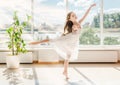 Cute little girl in a white dress dancing in a room front of the window Royalty Free Stock Photo