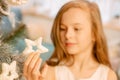 A cute little girl in a white dress holds a Christmas tree toy in her hand. child holding a star in his hands Royalty Free Stock Photo