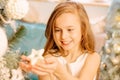 A cute little girl in a white dress holds a Christmas tree toy in her hand. child holding a star in his hands Royalty Free Stock Photo