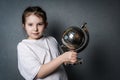Cute little girl in white t-shirt holding a globe and looking into the frame. Royalty Free Stock Photo