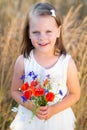 Cute little girl with wild flowers red poppy bouquet in the summer meadow Royalty Free Stock Photo