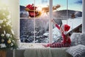 Cute little girl on window sill at home waiting for Santa Claus. Christmas celebration Royalty Free Stock Photo