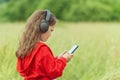 Cute little girl in wireless headphones holding smartphone and enjoying music outdoors Royalty Free Stock Photo