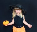 Cute little girl in witch costume with pumpkins. Halloween. On a black background. Royalty Free Stock Photo