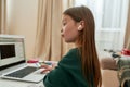 A cute little girl wondering what`s happening on the screen of her laptop during distance education while sitting alone Royalty Free Stock Photo