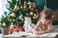 Cute little girl writing a letter to Santa near Christmas tree Royalty Free Stock Photo