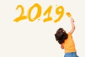 Cute little girl writing new year 2019 with painting brush Royalty Free Stock Photo