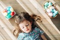 Little girl lying on a floor with colored Easter eggs in a basket Royalty Free Stock Photo