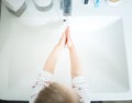 Cute little girl 2-3 years old washing hands with soap and water in bright bathroom. Top view Royalty Free Stock Photo