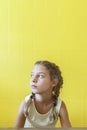 Cute little girl on yellow background with braids