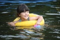 Cute little girl with yellow floaty swimming in the lake