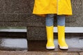 Cute little girl in yellow raincoat and rubber boots walking outdoor during rain. Bad weather, summer tropical storm, autumn Royalty Free Stock Photo