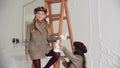 Cute little girls in coats and berets playing with elegant doll