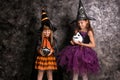 Cute little girls dressed as witches for Halloween near dark wall